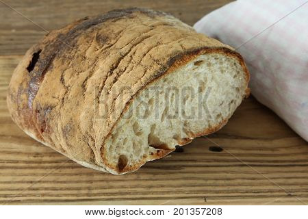 Fresh baked bread loaf with napking on wooden background