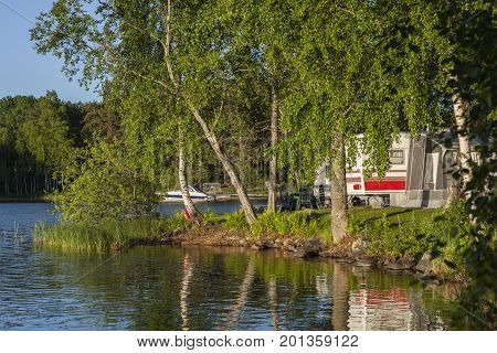 HEINOLA, FINLAND ON JULY 01. View of caravans on July 01, 2017, in Heinola Camping, Finland. Lake and trees this side, evening sunshine. Speedboat in the background. Editorial use.