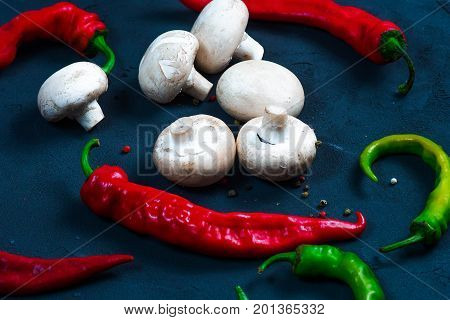 raw chicken wings with herbs in a transparent bowl Cauliflower with tomatoes and herbs and hot peppers with mushrooms on wooden background top view close up.
