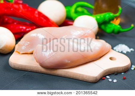 raw chicken wings with herbs in a transparent bowl Cauliflower with tomatoes and herbs and hot peppers with mushrooms on wooden background top view close up.