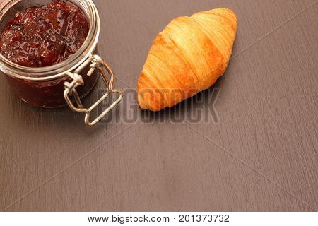French Croissant with jam jar on black background