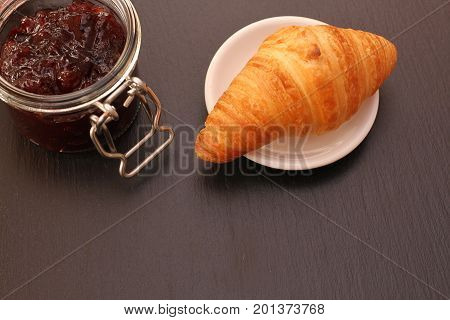 French Croissant with jam jar on black background
