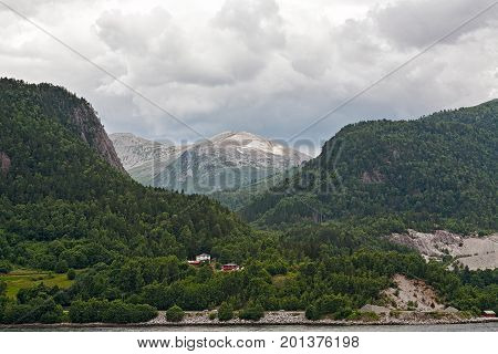 Small houses in the mountains along the Romsdalsfjorden near Andalsnes under a cloudy sky Norway
