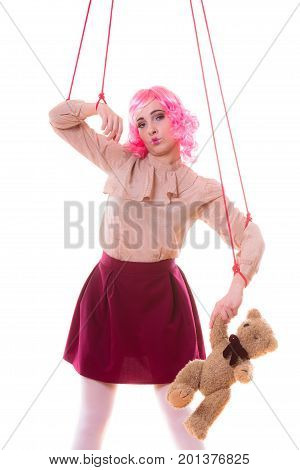 Mental disorder concept. Young woman girl stylized like marionette puppet on string with teddy bear toy isolated on white background