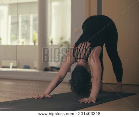 A young woman performing yoga-asanas in the hall. Artha mukha svanasana.