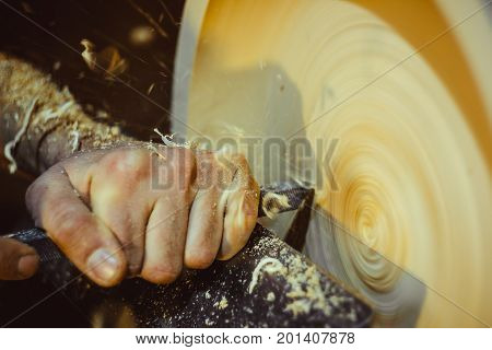 man turning a wooden plate on a lathe