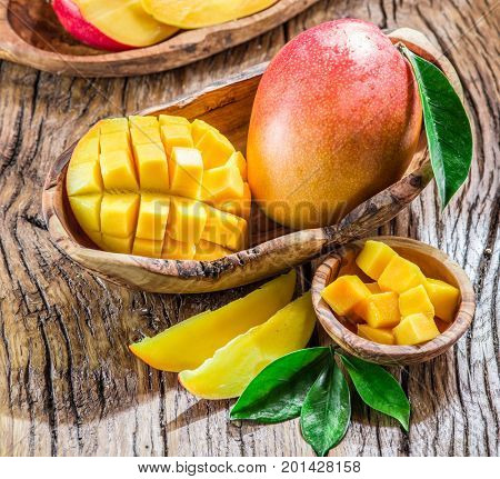 Mango fruit and mango cubes on the wooden table.