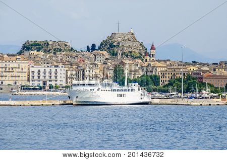 Corfu Greece - June 7 2017: Old Corfu town with the Venetian Old Fortress the bell tower of the Saint Spyridon Church and a ferry boat as seen from the harbor