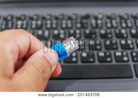 Young man holding LAN cord in the hand with blur computer background