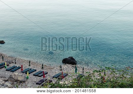 ULCINJ, MONTENEGRO - JULY 30, 2017: Small rock beach Liman on the Adriatic Sea in Ulcinj, Montenegro. Early morning time with empty beach beds, closed umbrellas and without people.