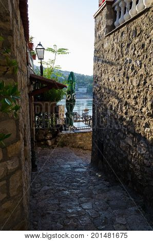 ULCINJ, MONTENEGRO - AUGUST 1, 2017: Old narrow street in Stari Grad of Ulcinj, Montenegro. The fortress in the Old town in a sunny summer day.