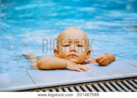Portrait of beautiful baby girl with seriously face in swimming pool
