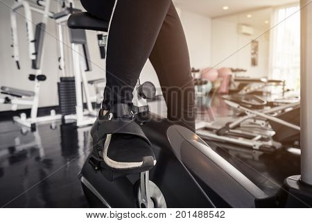 Young asian woman exercising on the xtrainer machines in gym