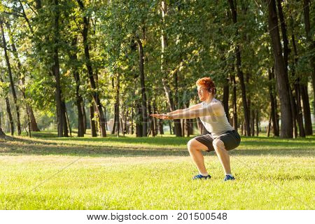 Sit ups. Young adult redhead man having intensive training outdoors in morning