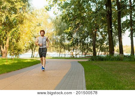 Redhead and freckled man running in park at summer morning. Healthy lifestyle concept