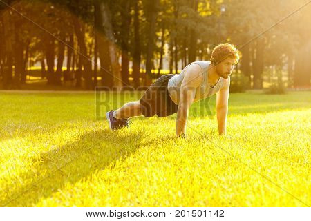 Seriosly bearded redhead athlete concentrate and doing plank. Outdoor