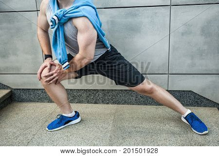 Fitness young man in sportswear doing yoga fitness exercise in the city street over gray concrete background. Outdoor sports clothing and shoes urban style. Sneakers close up.
