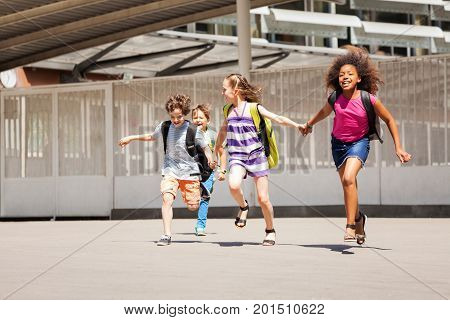 Diverse group of kids running from school happy smiling and holding hands