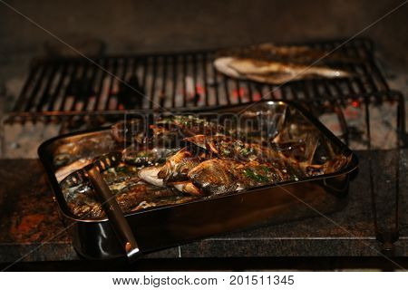 Fish grill / There are fish on the grill and grilled. An raw freshwater fish on the grill. Cooked in traditional style. Cooking of salted fish on a grill stove.