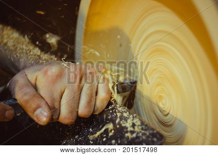 man turning a wooden plate on a lathe
