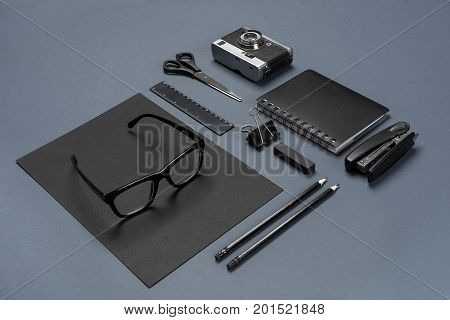 A set of black office accessories, glasses and old camera on gray background. Flat lay. Still life. Mock-up