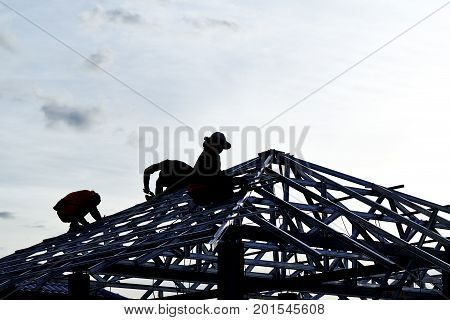 Contractor in Silhouette working on a Roof Top with Sky in background
