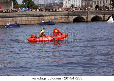 Red lifeguard rescue boat with lifeguards sailing in a channel with spectators on a bridge, Copenhagen, August 26, 2017