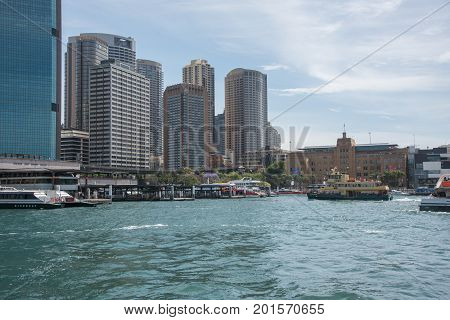 SYDNEY,NSW,AUSTRALIA-NOVEMBER 20,2016: Circular Quay with tourists on ferry transport, terminal and cityscape under a blue sky with clouds in Sydney, Australia