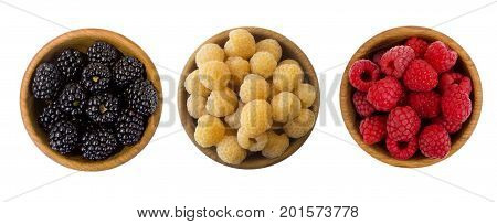 Black red and yellow berry in a wooden bowl isolated on white background. Raspberries and blackberries on white. Vegetarian or healthy eating. Juicy and delicious berries with copy space for text. Top view.