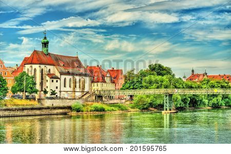St. Oswald Church with Eiserner Steg bridge across the Danube River in Regensburg - Germany