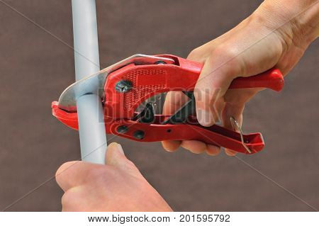 Using a cutter for plastic pipes when repairing domestic water pipes hand plumbing close-up.