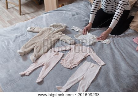 Baby's clothes laid out on bed, natural light