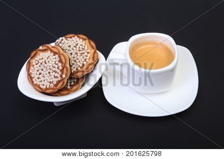 Classic espresso in white cup with homemade cake on black background. Selective focus