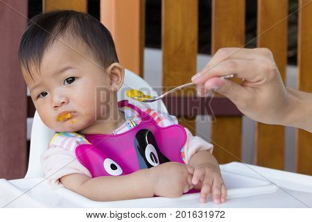 Asian cute baby boring eat food Mother feeding solid food for young kid eight month.
