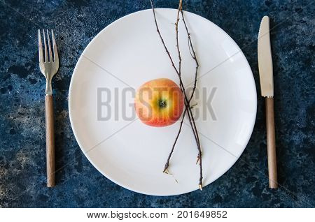 White Plate, Red Apple, Cutlery And Tree Brunches On A Blue Stone Background. Autumn, Thanksgiving,
