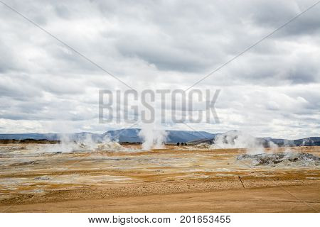 Mudpot in the Namafjall geothermal area, Iceland - area around boiling mud is multicolored and cracked.