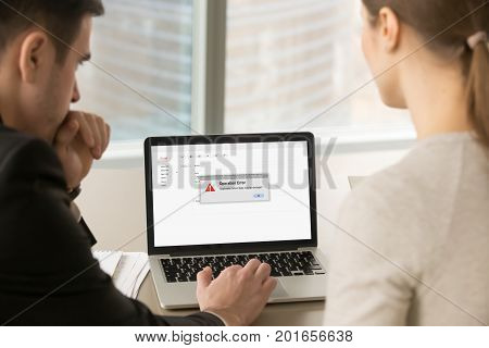 Computer error in office, businessman and businesswoman looking at laptop screen with reporting pop up message about application failure, pc crash, email app failed with data loss, close up back view