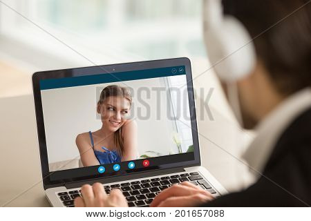 Shy teen girl on video call with boyfriend, couple talking by videoconferencing app, young woman embarrassed during virtual chat with man, distance relationships, focus on screen, close up rear view