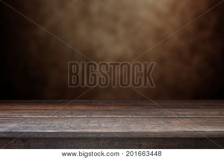 Old wood table with dark brown wall blurred background.