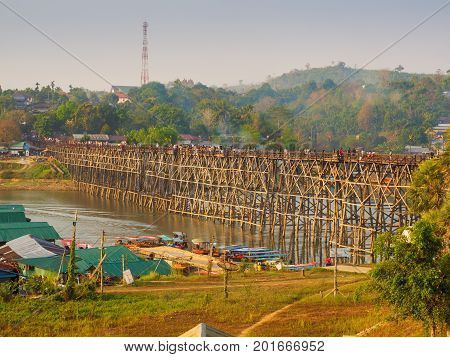 Sangkhlaburi Thailand - March 05 2017: The scenery of the Mon wooden bridge over the river in Sangkhlaburi District Kanchanaburi Province Thailand while tourists walking across the bridge on the morning of March 05 2017