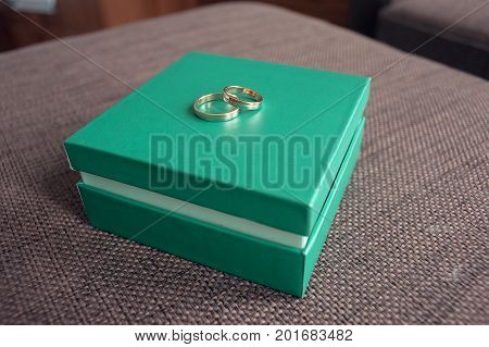 Wedding rings for a newly-married couple, lie on a light green box