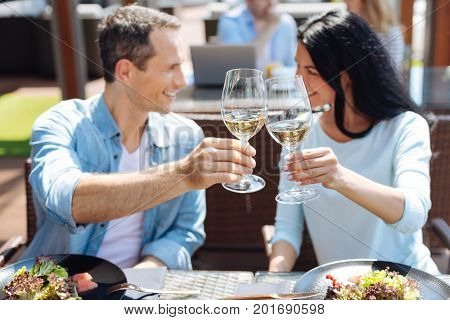 Our anniversary. Selective focus of glasses with wine being in hands of nice happy delighted couple while celebrating their anniversary
