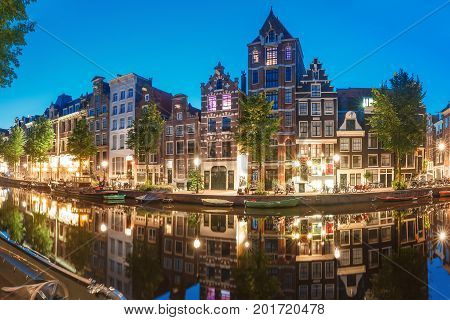 Amsterdam canal Herengracht with typical dutch houses and their reflections during morning blue hour, Holland, Netherlands.