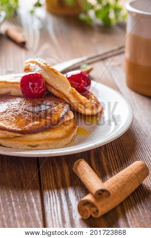 Homemade Pancakes with Cherry Cinnamon and Honey for a Breakfast on Wooden Table