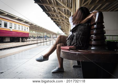 Sadness Exhausted Tired Illness of Young Woman. Asian Female backpacker is waiting a train at Thai train station.