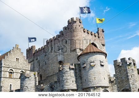 Medieval castle Gravensteen - Castle of the Counts with small windows surrounded by water in moat in Ghent, Flanders, Belgium.
