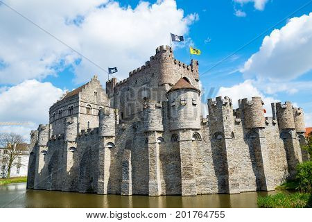 Medieval castle Gravensteen - Castle of the Counts with small windows surrounded by water in moat in Ghent, Flanders, Belgium.