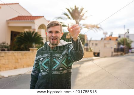 Happy young man showing off the key to his new home. Owner, real estate and people concept.