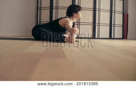 A young woman performing yoga-asanas in the hall. Prasarita padotanasana