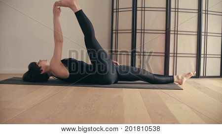 A young woman performing yoga-asanas in the hall. Supata padangushthasana